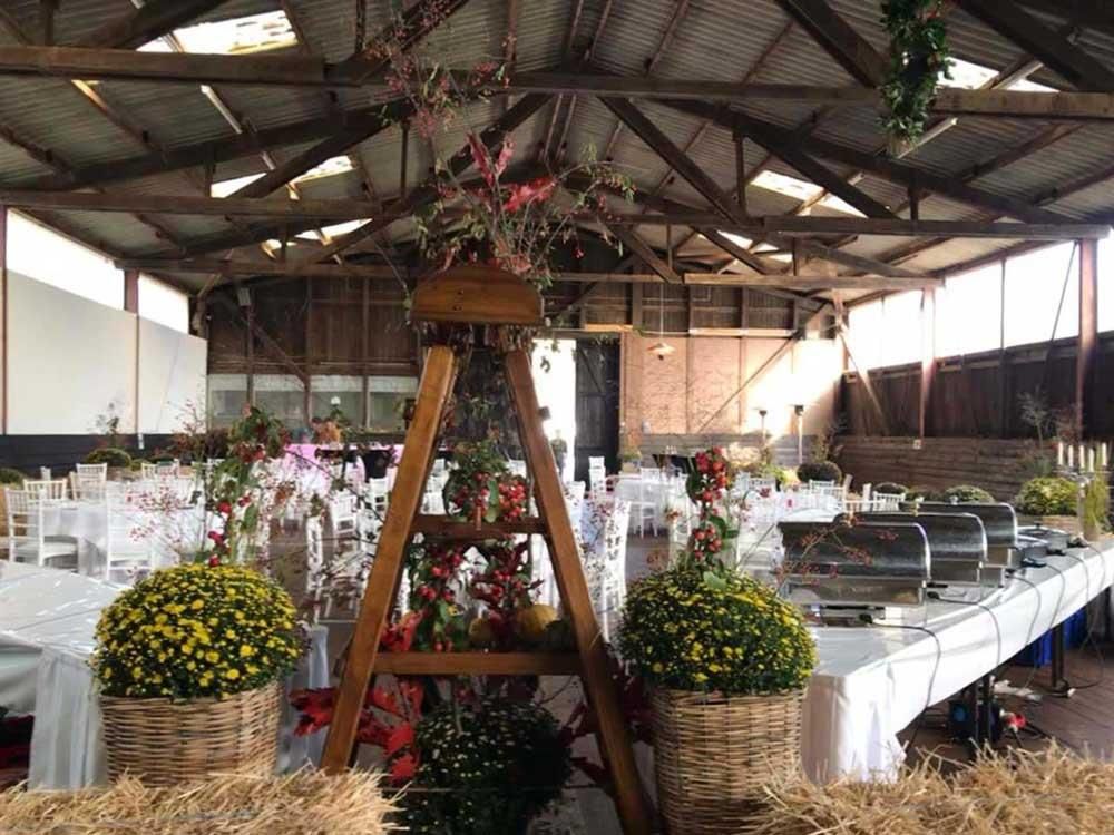 Ein großer Raum mit Tischen und Stühlen, dekoriert für einen Hochzeitsempfang.