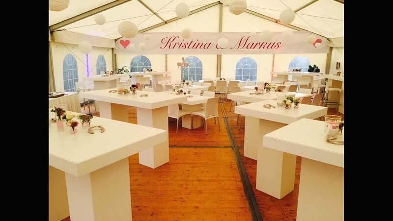 Ein Zelt voller weißer Tische und Stühle für einen Hochzeitsempfang.