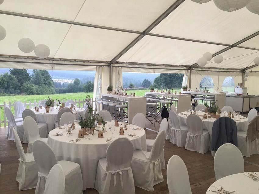 Ein großes Zelt mit Tischen und Stühlen für einen Hochzeitsempfang.