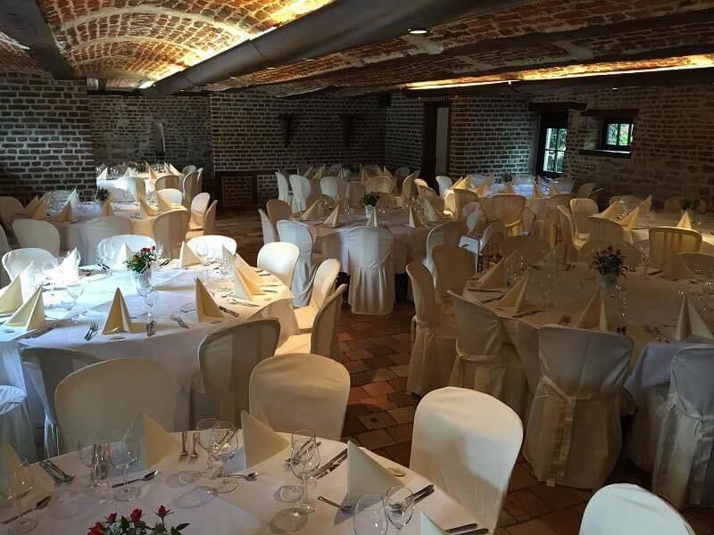 Ein großer Raum voller Tische und Stühle, aufgestellt für einen Hochzeitsempfang.