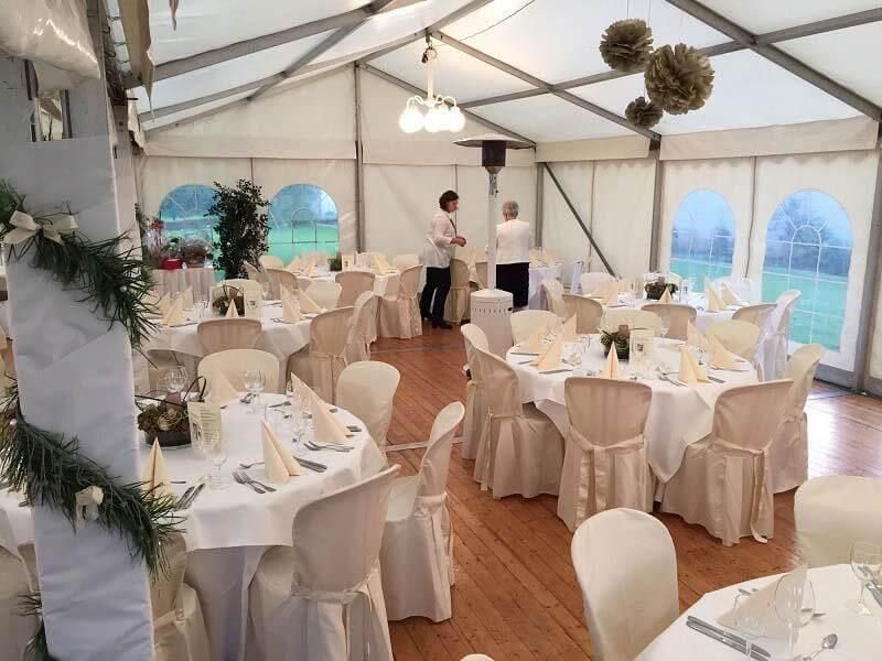 Ein großes Zelt mit Tischen und Stühlen für einen Hochzeitsempfang.