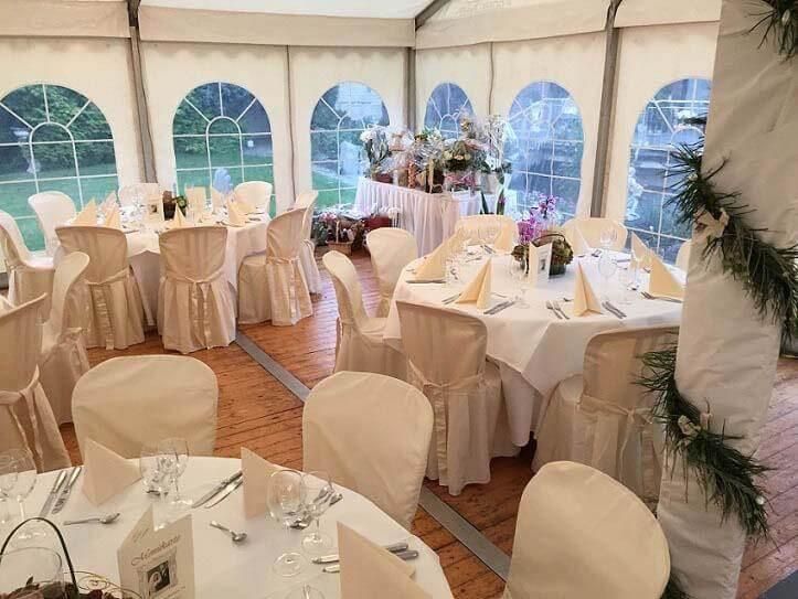 Ein Zelt mit Tischen und Stühlen für einen Hochzeitsempfang.