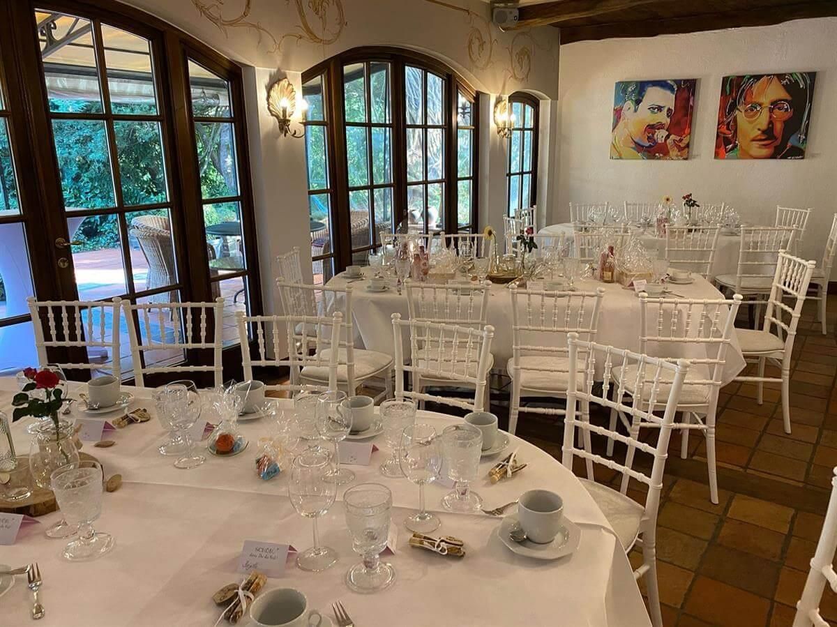 Ein Raum mit Tischen und Stühlen, der für einen Hochzeitsempfang aufgestellt ist.