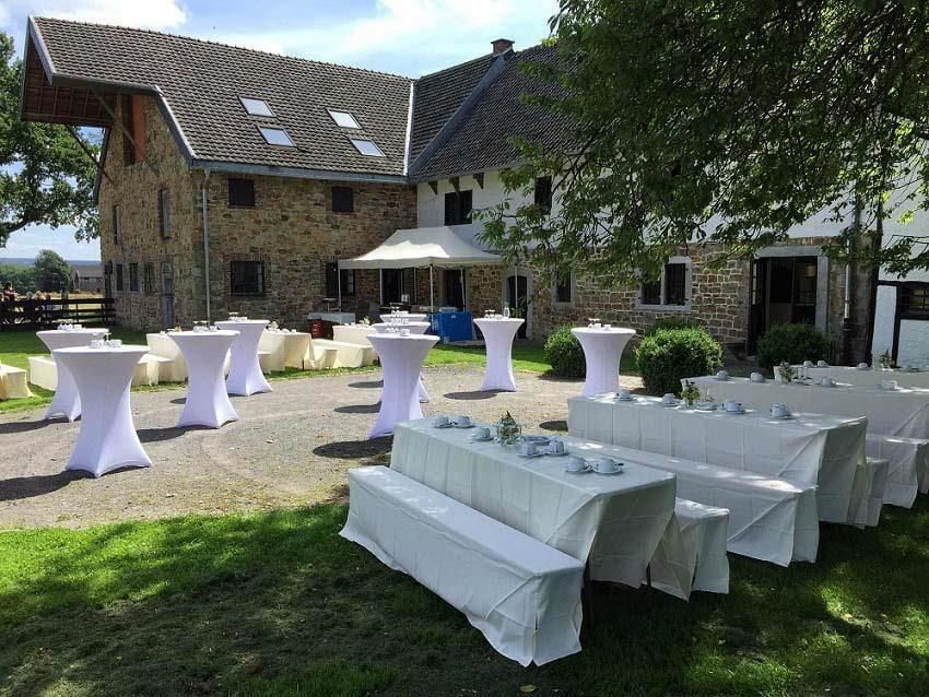 Eine Reihe weißer Tische und Bänke vor einem Steingebäude.