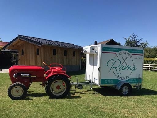 Ein roter Traktor steht neben einem weißen Anhänger.