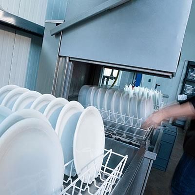 Eine Person lädt Teller in eine Spülmaschine.