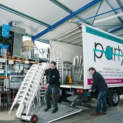 Zwei Männer laden Stühle in einen Partytruck