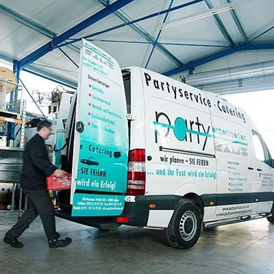 Ein Mann lädt etwas in einen Partyservice-Van