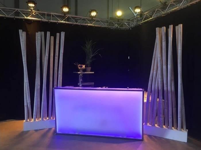 Eine Bar mit violettem Licht ist von Bambusstäben umgeben.