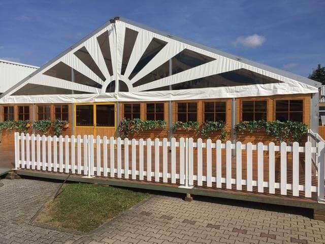 Ein weißer Zaun umgibt ein großes weißes Zelt