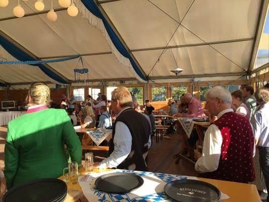 Eine Gruppe von Menschen sitzt an Tischen in einem Zelt