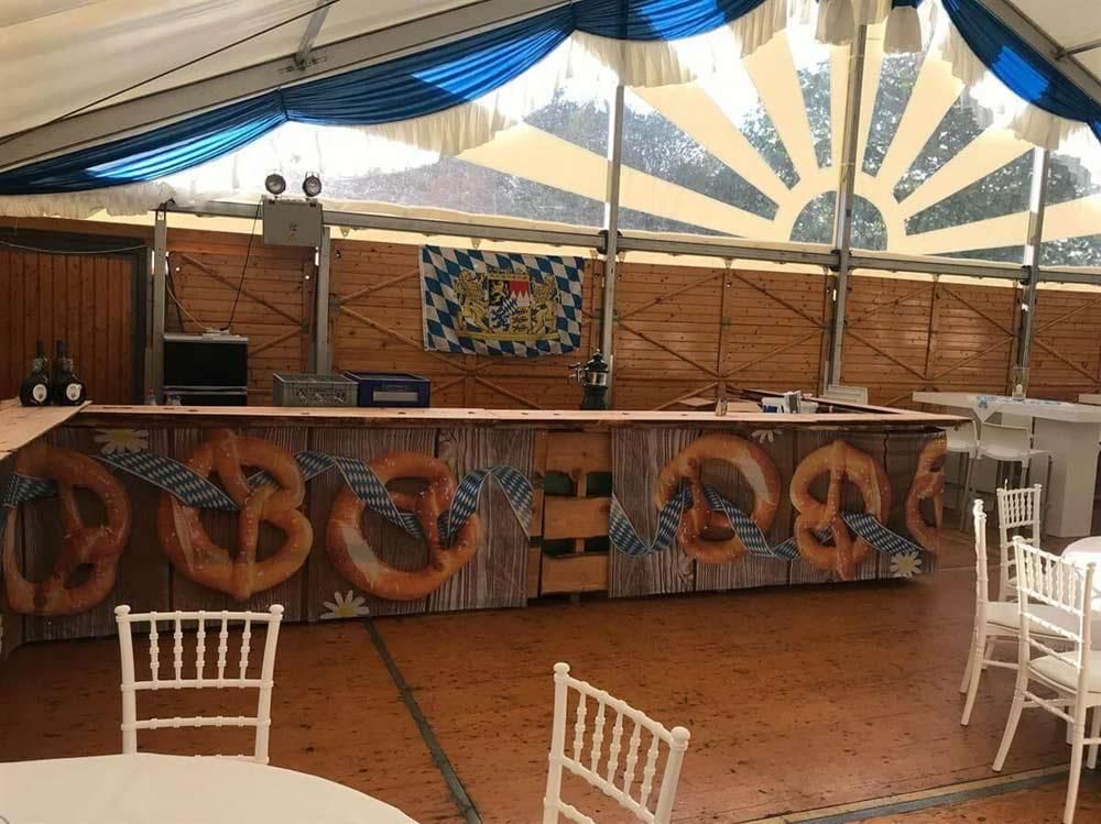 Ein Zelt mit Tischen und Stühlen und einer Bar mit Brezeln darauf