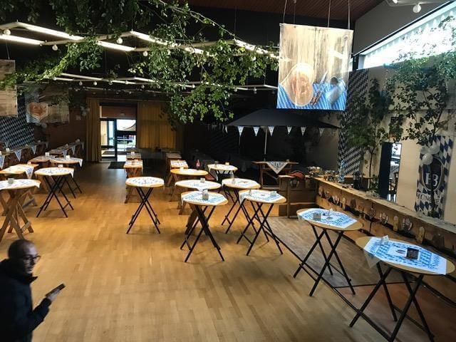 Ein Mann schaut in einem Raum mit Tischen und Sonnenschirmen auf sein Telefon.