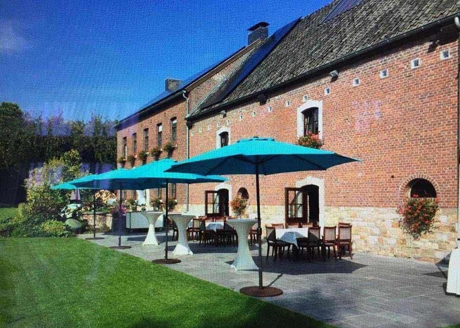 Vor einem Backsteingebäude ist eine Reihe blauer Regenschirme aufgestellt.