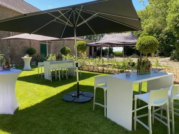 Es gibt Tische und Stühle unter Sonnenschirmen im Gras.