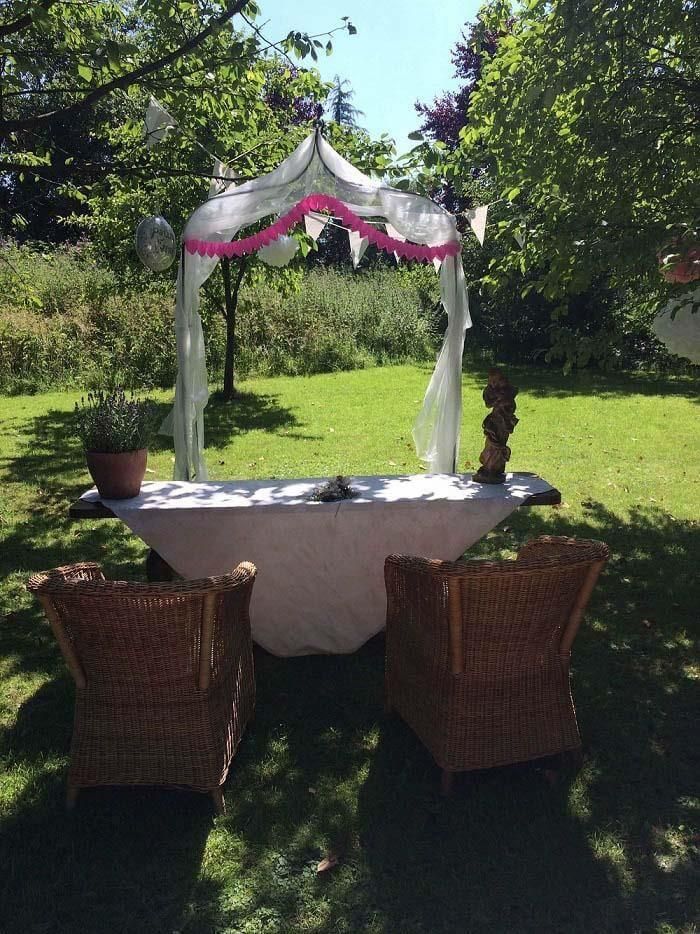 Zwei Korbstühle sitzen unter einem Baldachin im Gras