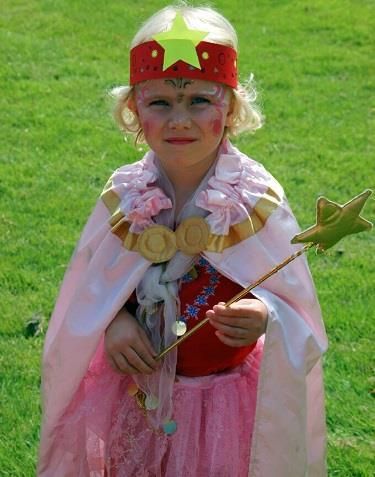 Ein kleines Mädchen trägt einen rosa Umhang und hält einen Zauberstab.