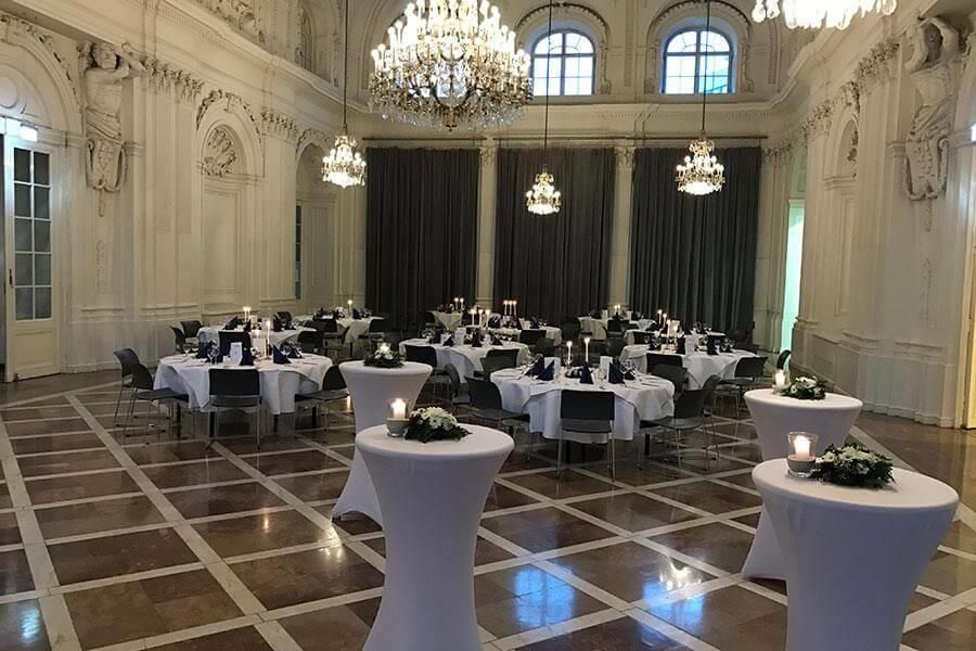 Ein großer Raum mit Tischen und Stühlen und einem Kronleuchter.