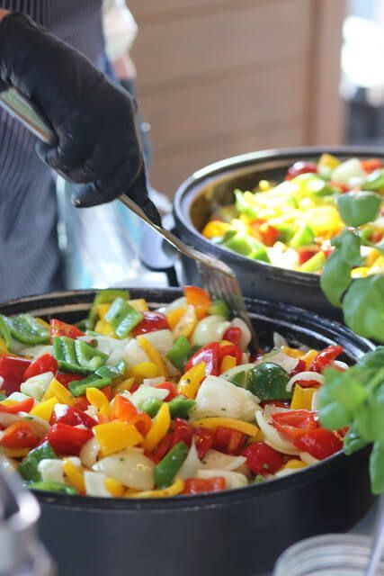 Eine Person rührt mit einem Spatel in einer Schüssel Gemüse um.