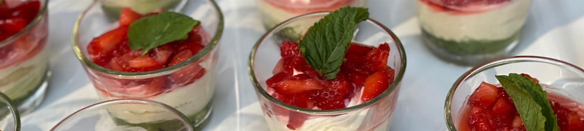 Eine Gruppe von Gläsern gefüllt mit Erdbeeren und Minzblättern.