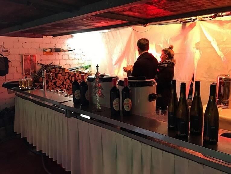 Ein Mann und eine Frau stehen hinter einer Bar voller Weinflaschen.