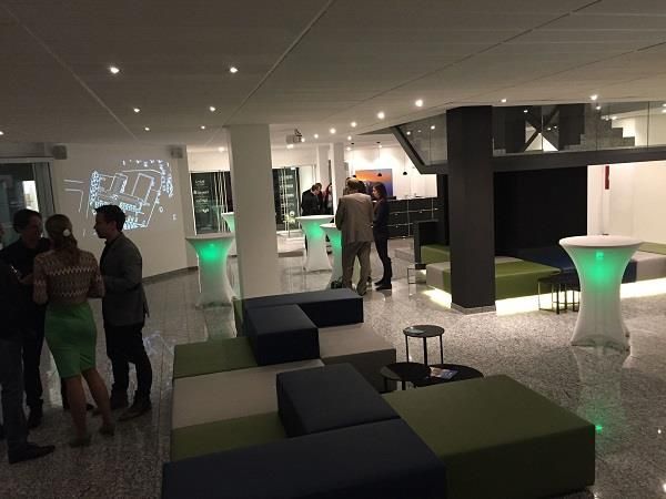 Eine Gruppe von Leuten steht in einem Raum mit Tischen und Stühlen.