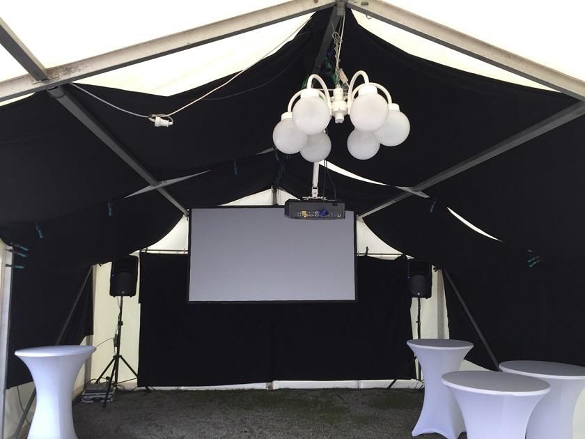 Eine Projektionsleinwand hängt von der Decke eines Zeltes