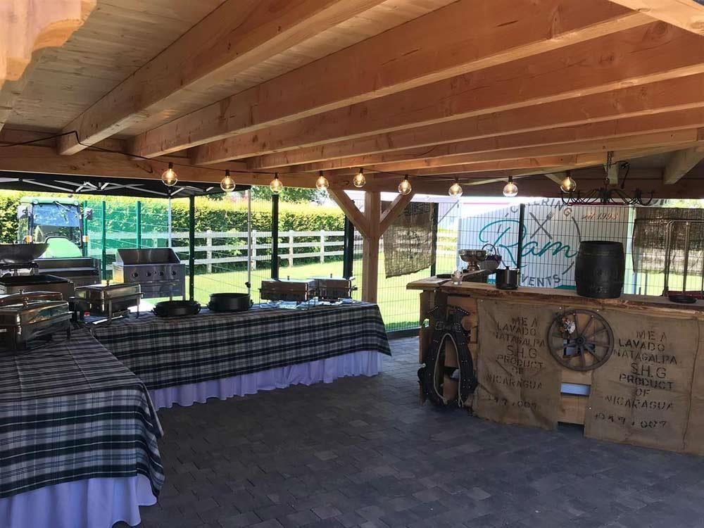 Ein überdachter Bereich mit Tischen und einer Bar unter einem Holzdach.