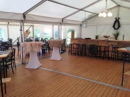 Ein großer Raum mit Tischen und Stühlen unter einem Zelt