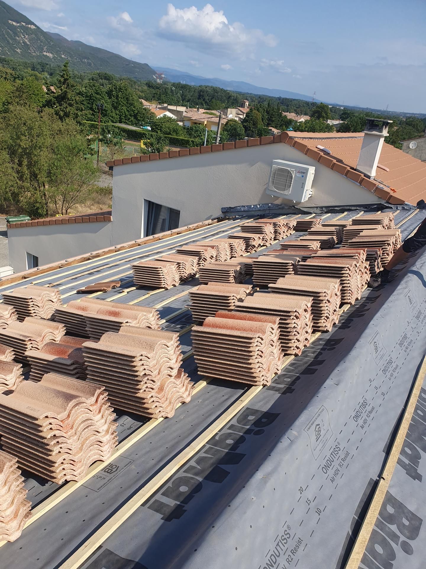 Toiture en construction avec briques empilées, membranes d'étanchéité et collines en arrière-plan