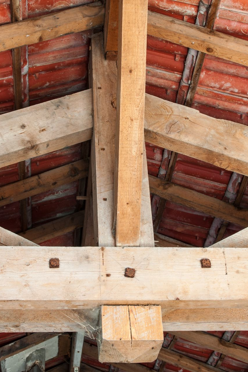 Poutres de toit en bois et tuiles en terre cuite rouge vues d'en bas sous un plafond rustique