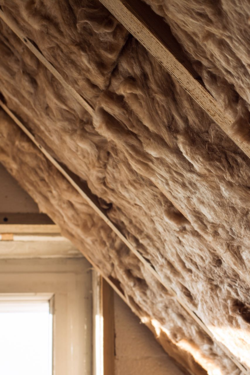 Isolation apparente et chevrons en bois dans le plafond du grenier au-dessus d'une fenêtre.
