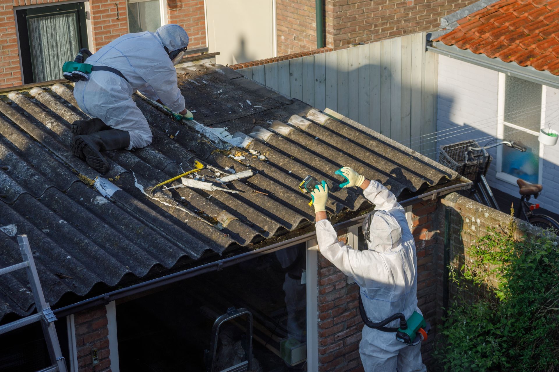Deux ouvriers décontaminent le toit d'une maison