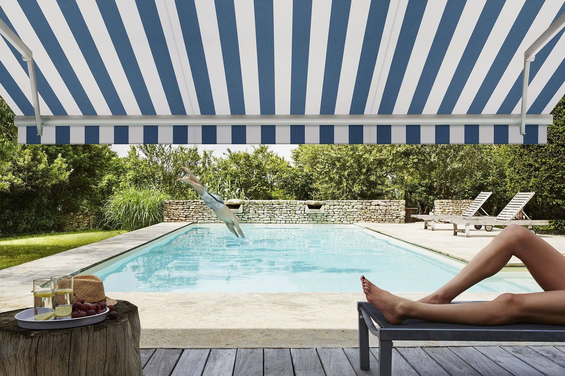 Un store rayé sur une terrasse près d'une piscine