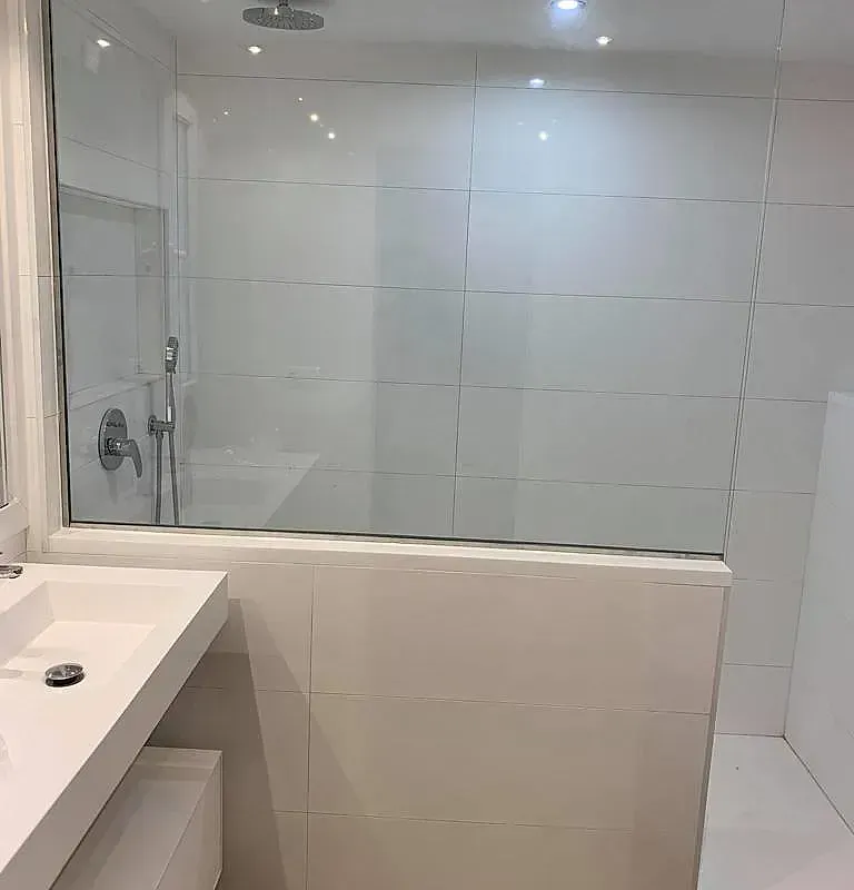 Un baño con lavabo y ducha con puerta de cristal.