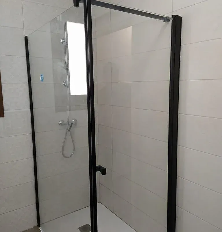 Un baño con cabina de ducha y marco negro.