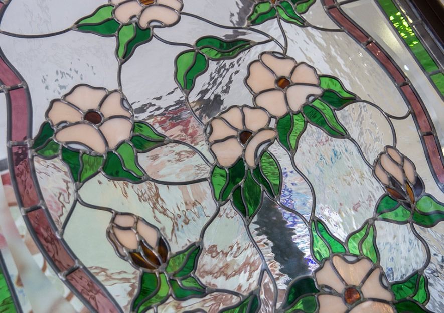 Una vidriera con flores rosas y hojas verdes.
