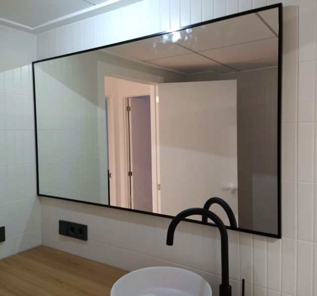 Un baño con un gran espejo y un lavabo.
