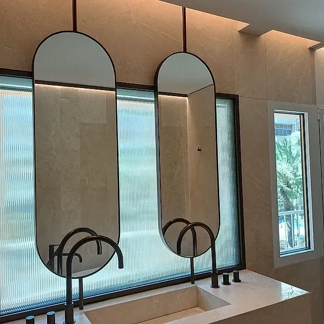 Un baño con dos espejos y un lavabo frente a una ventana.