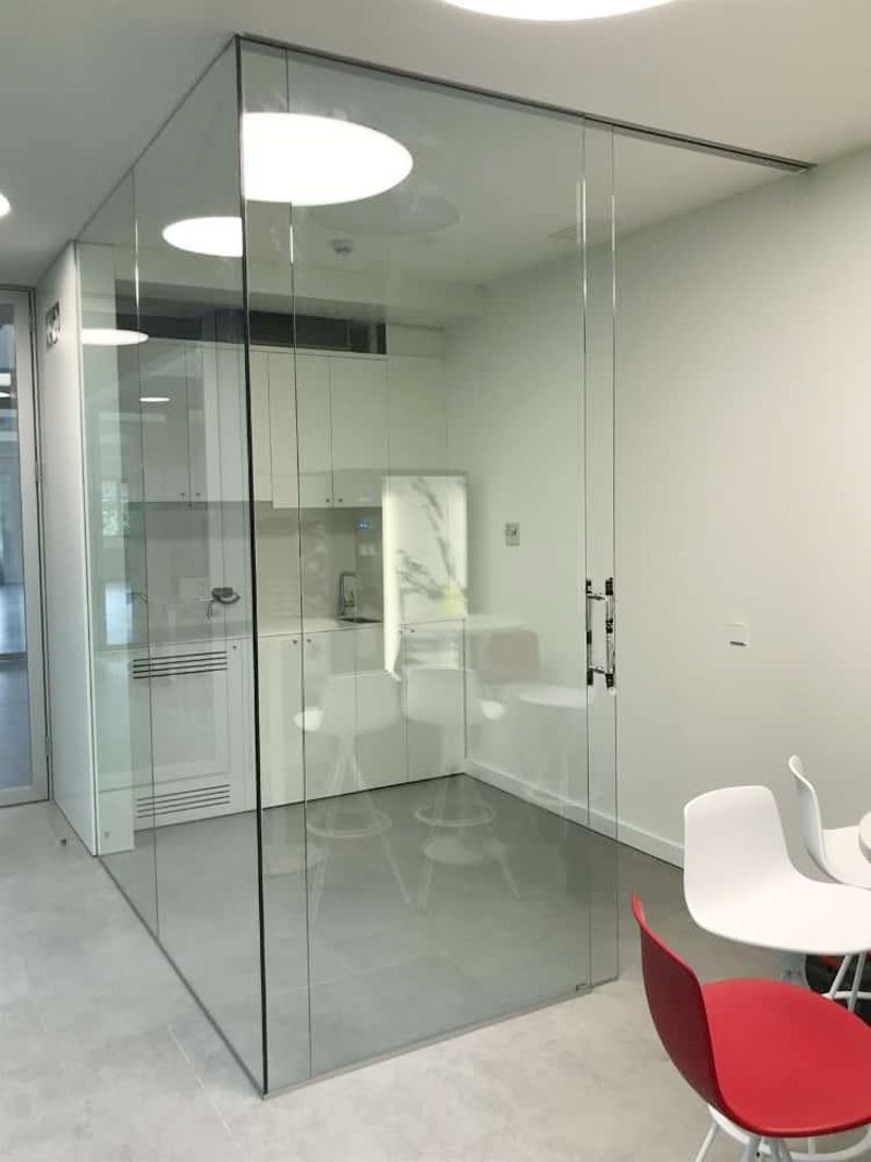 Una habitación con una pared de cristal y una mesa y sillas.