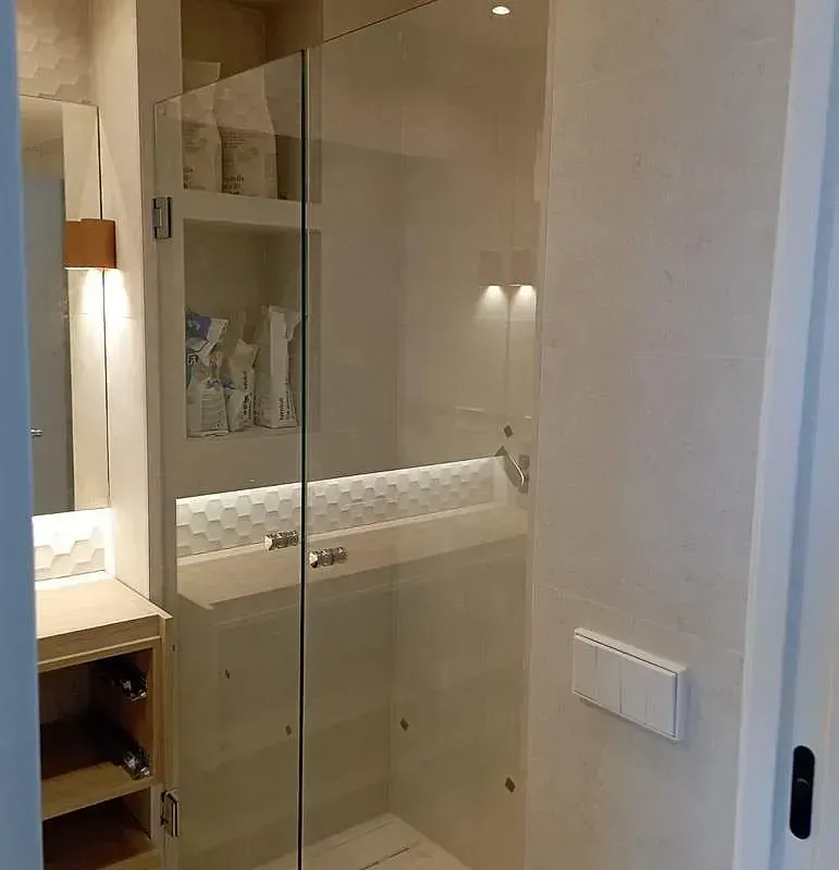 Un baño con puerta de ducha de cristal y lavabo.