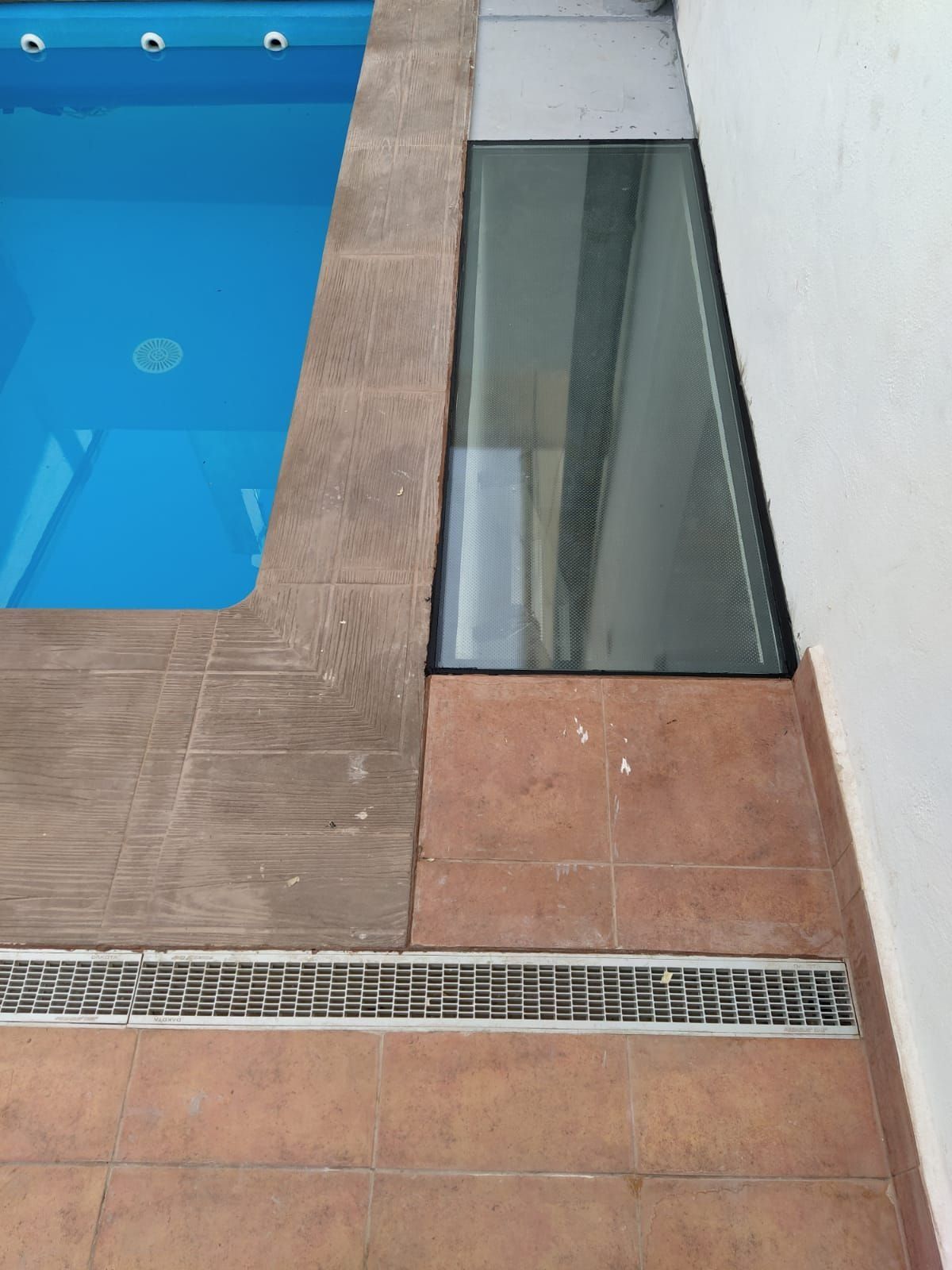 Una piscina con una puerta de cristal en el lateral.
