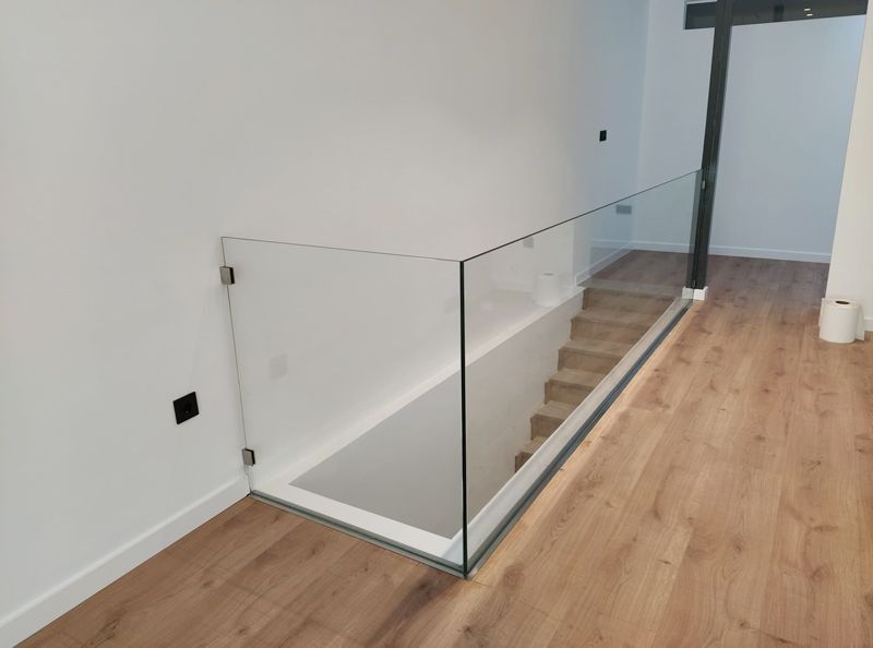 Una escalera con barandilla de cristal y suelo de madera.