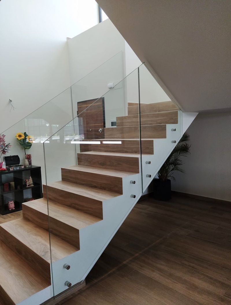 Una escalera de madera con barandilla de cristal en una casa.