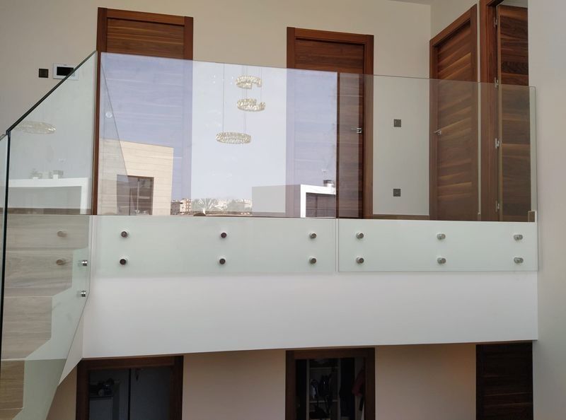 Un balcón con barandilla de cristal y escaleras en una casa.