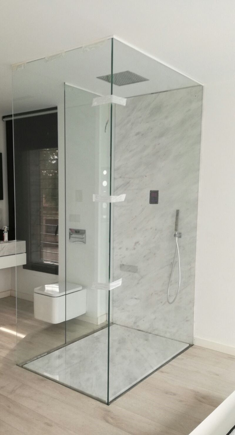 Un baño con ducha a ras de suelo y un inodoro.