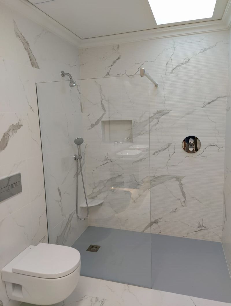 Un baño con inodoro y ducha a ras de suelo.