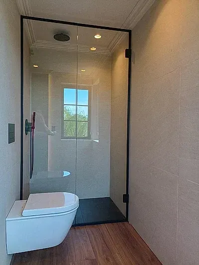 Un baño con inodoro y puerta de ducha de cristal.