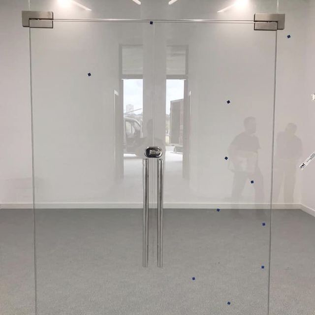 Una habitación con una puerta de cristal y el reflejo de una persona en la ventana.