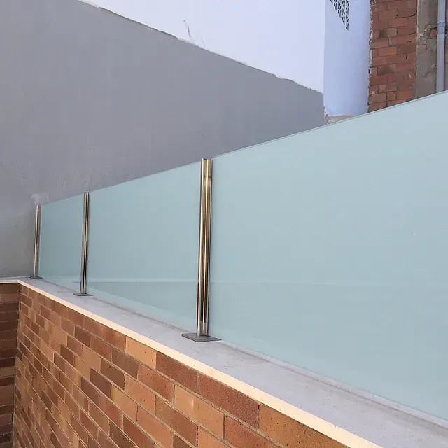 Una pared de ladrillos con una valla de vidrio delante.